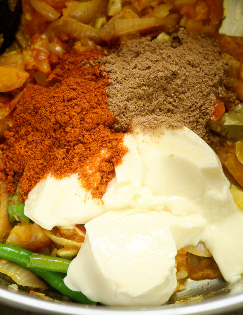 adding yoghurt, red chilli powder, curry powders to the cooked onions and chopped tomatoes.