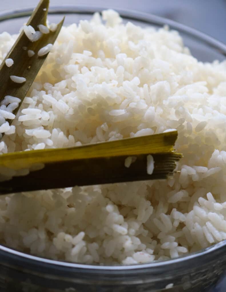 cooking rice on stove top with pandan leaves.