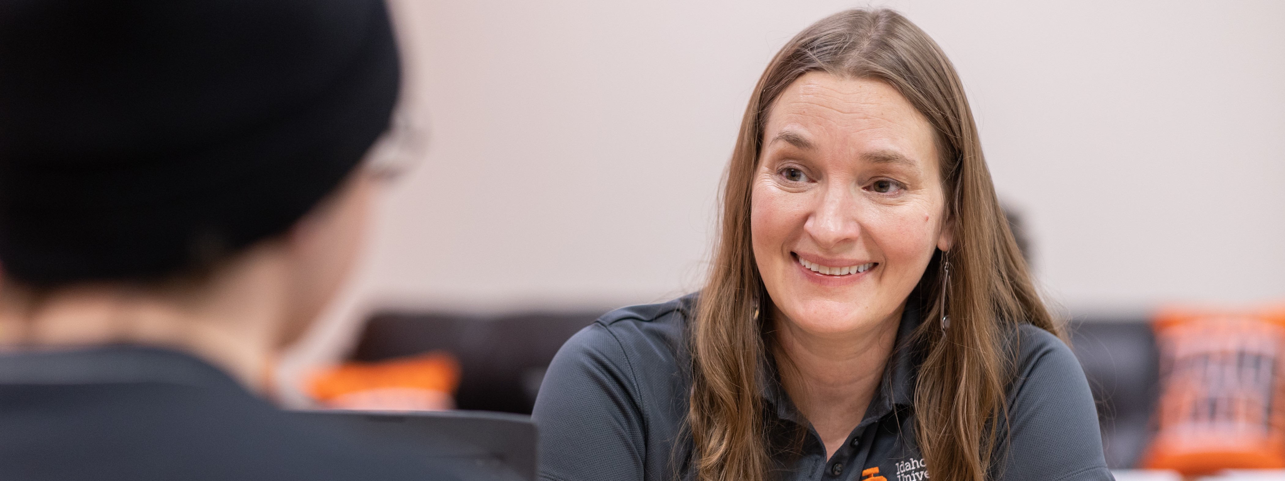 A woman smiling as she helps advise a student