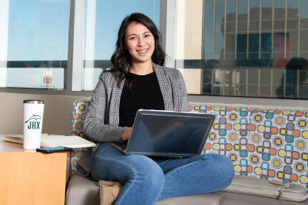 Student seating at a study room with laptop in hand.