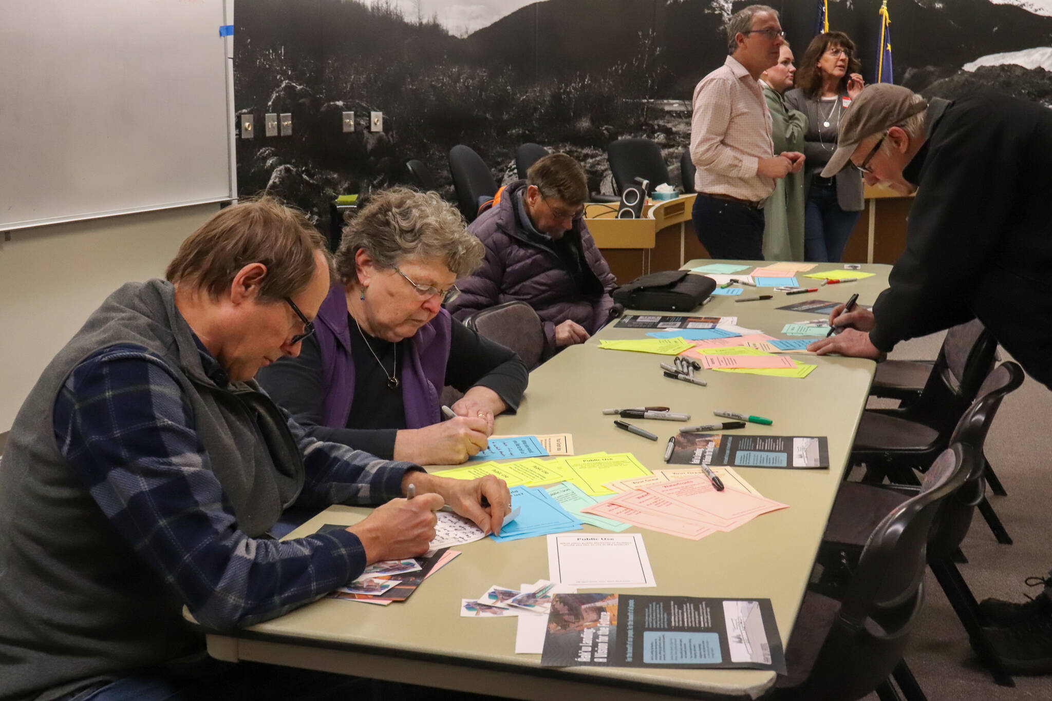 Juneau residents fill out public comment cards at an open house in the Assembly Chambers on Jan. 22, 2025. (Jasz Garrett / Juneau Empire)