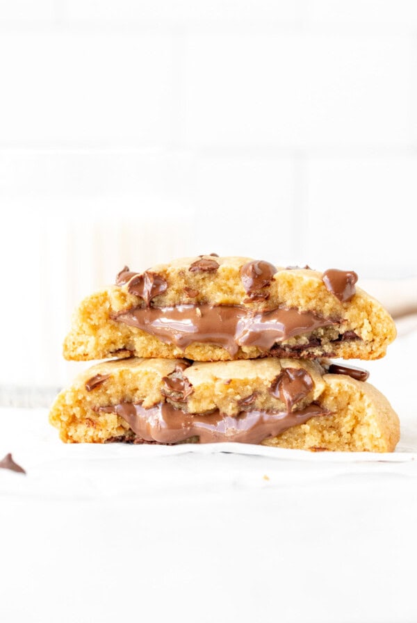 Single serving chocolate chip cookie stuffed with Nutella, broken in half with cookie halves placed on top of each other