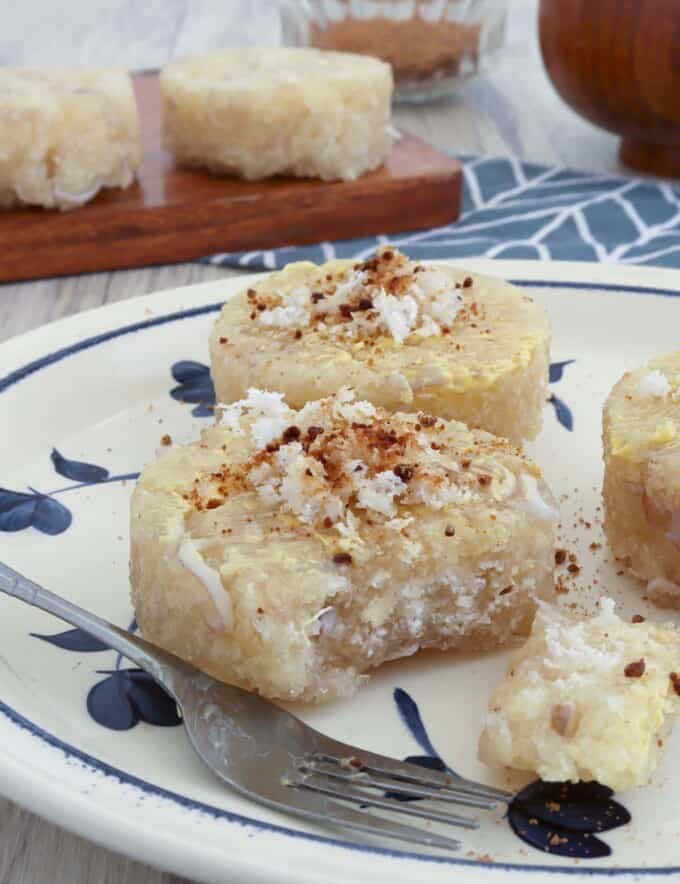 eating steamed cassava cakes topped with grated coconut on a plate