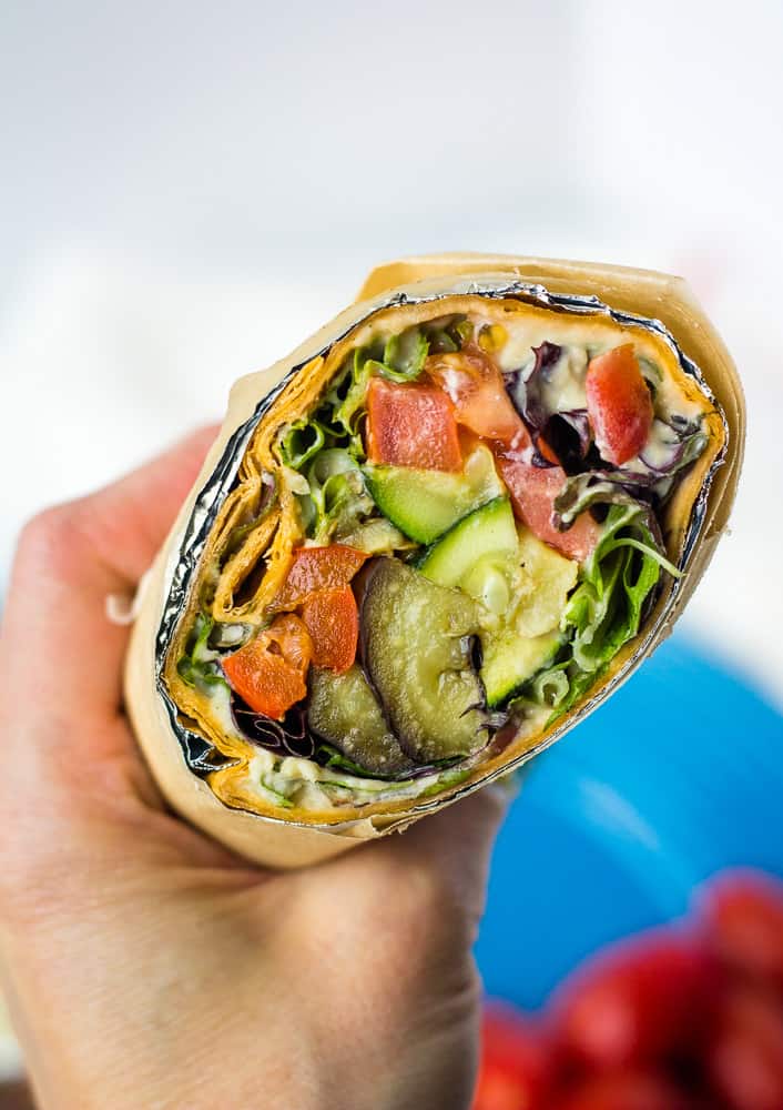 Hand holding lavash wrap sandwich.