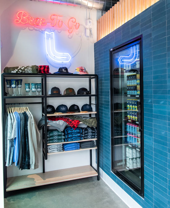 Beer To Go neon sign, wall of various merchandise and window displaying cans of beer