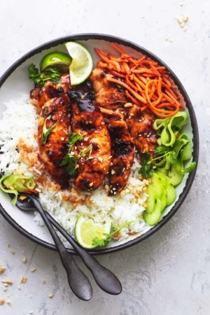 overhead view of plate with grilled chicken, julienned carrots, cucumber ribbons, and lime wedges