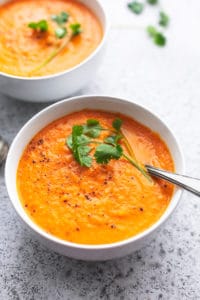 bowl of carrot soup with fresh cilantro garnish and spoon