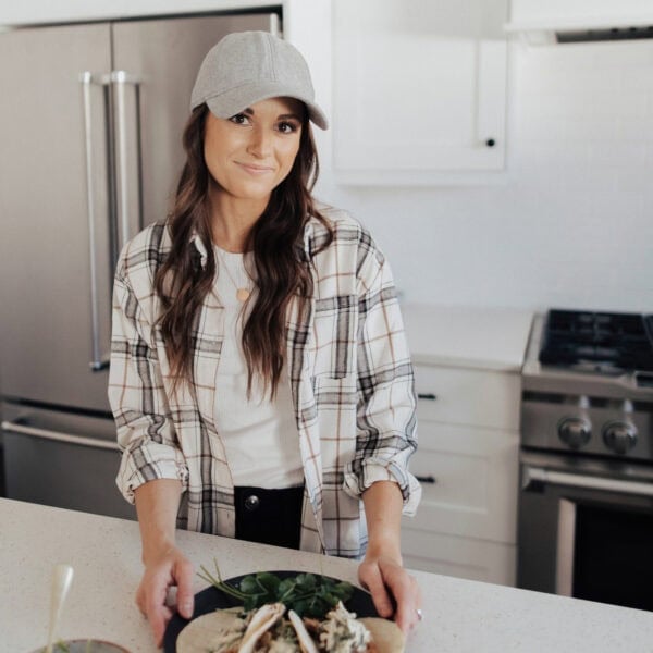 woman standing at kitchen counter with plate of tacos