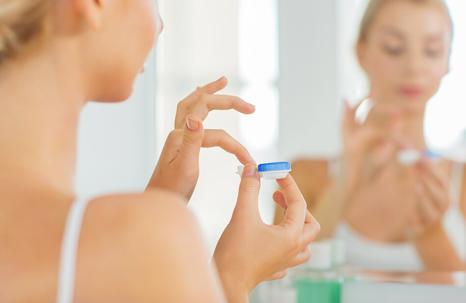 woman with contact lenses case in mirror taking contact lenses out