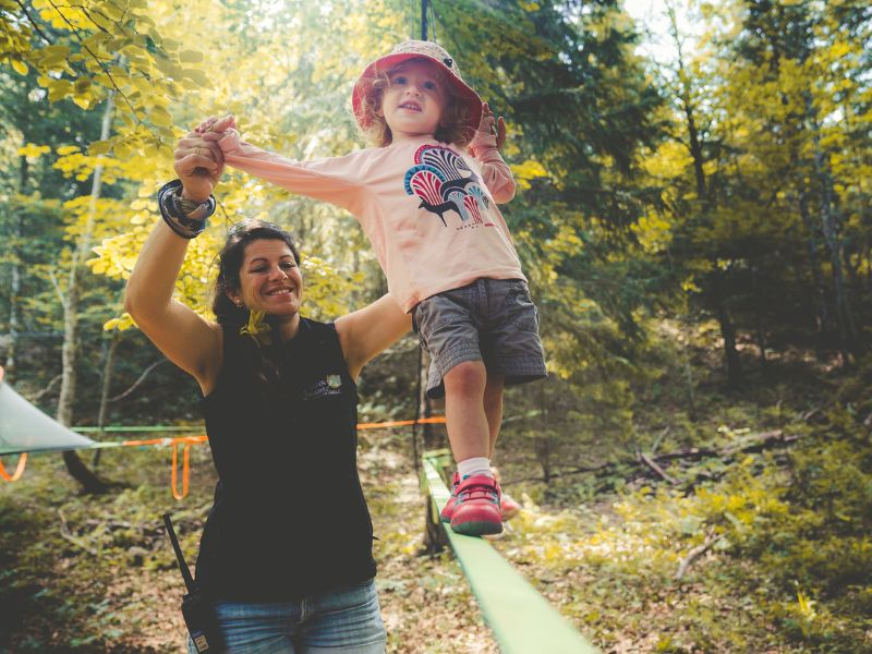 une jeune femme guide une fillette sur une slackline