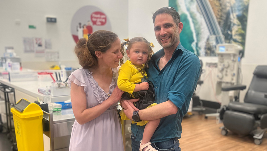 Woman and man smiling in a donor centre holding their young daughter