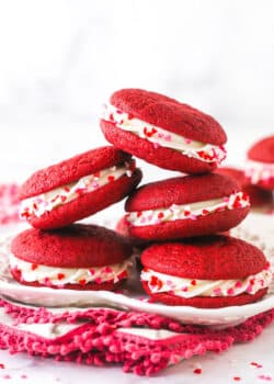 A pile of red velvet cookie sandwiches on a plate