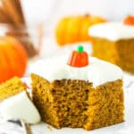 A piece of pumpkin cake on a plate with one bite on a metal dessert fork