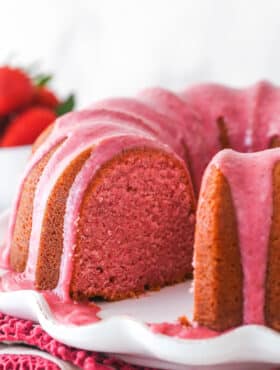 Strawberry pound cake on a serving platter with a slice taken out of it.