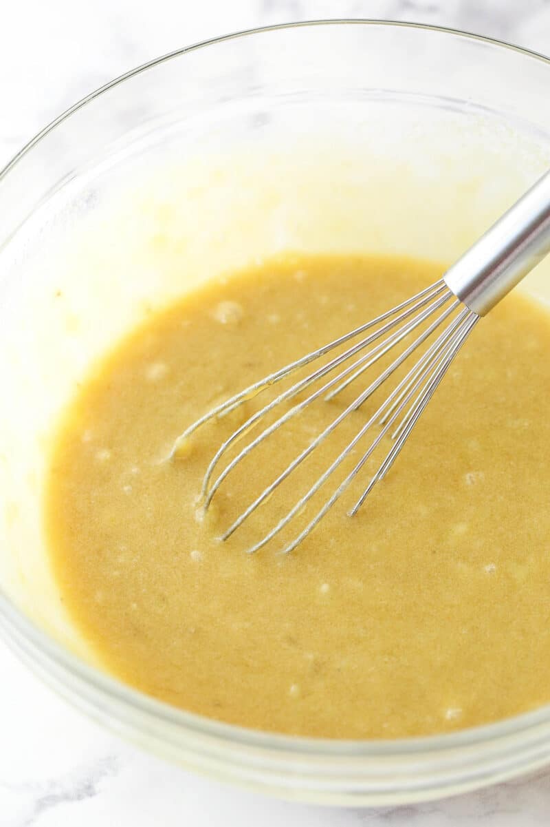 Glass mixing bowl with mashed bananas mixed into the batter for Moist Banana Oatmeal Cookies.