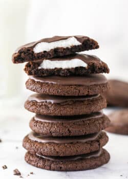 A stack of chocolate marshmallow cookies, with one cut in top on half to show the marshmallow inside