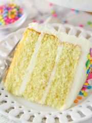 A slice of moist vanilla layer cake on a plate with a fork.