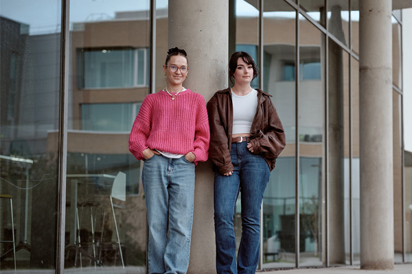 Two students stood by a pillar