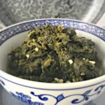 side view of blue and white bowl filled with green spinach