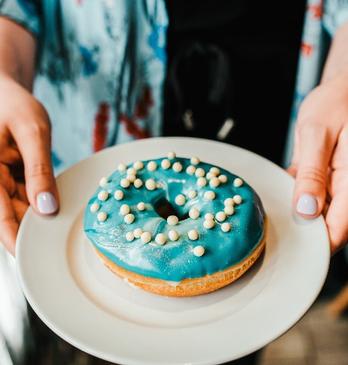 Woman holding a vanilla donut from Happiness Cafe located in London, Ontario