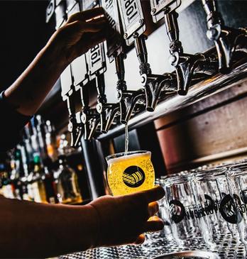 A bartender filling up a glass of draft beer in a bar located in London, Ontario