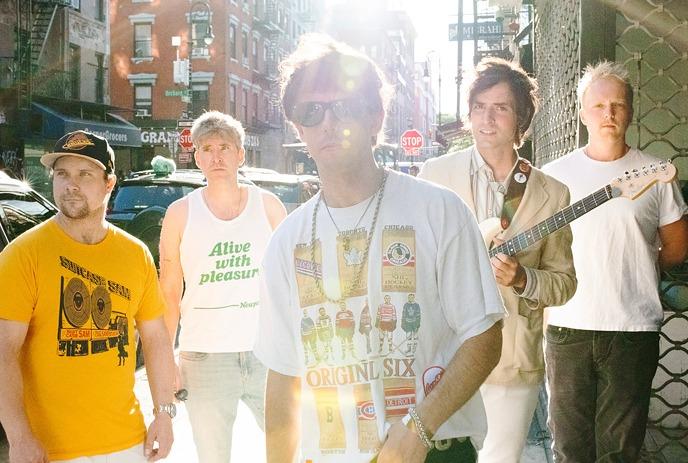 The Brokes stand on a city street with sunlight creating a lens flare.