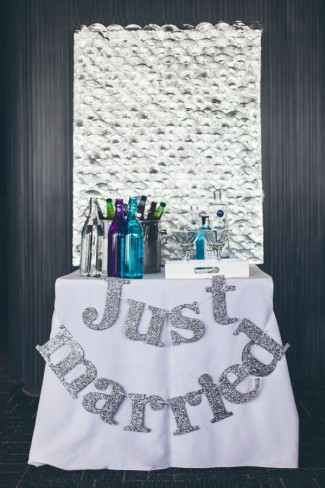 Bar table with silver glitter "Just married" sign hanging from table