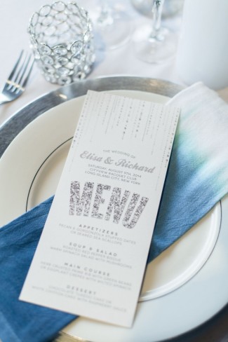 White menu with silver sparkle writing on top of blue ombre napkin and silver charger