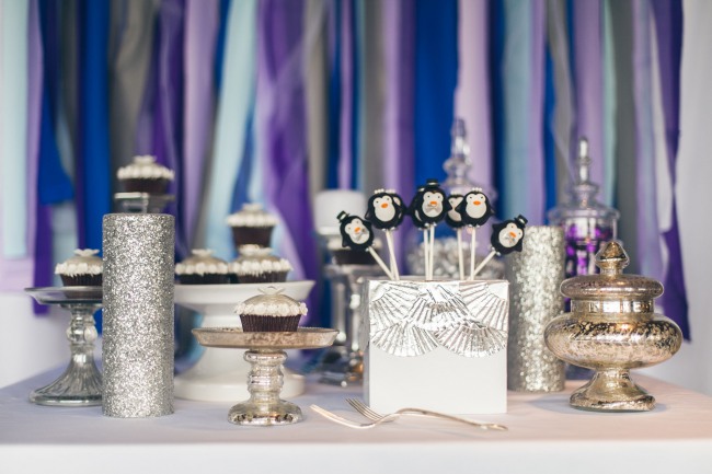 Silver themed dessert table with a purple and blue crepe paper back ground 