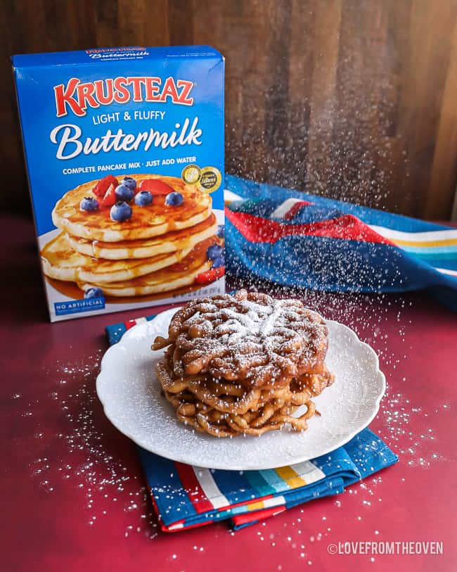 Funnel cake being sprinkled with powdered sugar