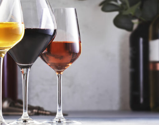 Wines assortment. Red, white, rose wine in glasses and bottles on gray table background. Wine bar, shop, tasting concept