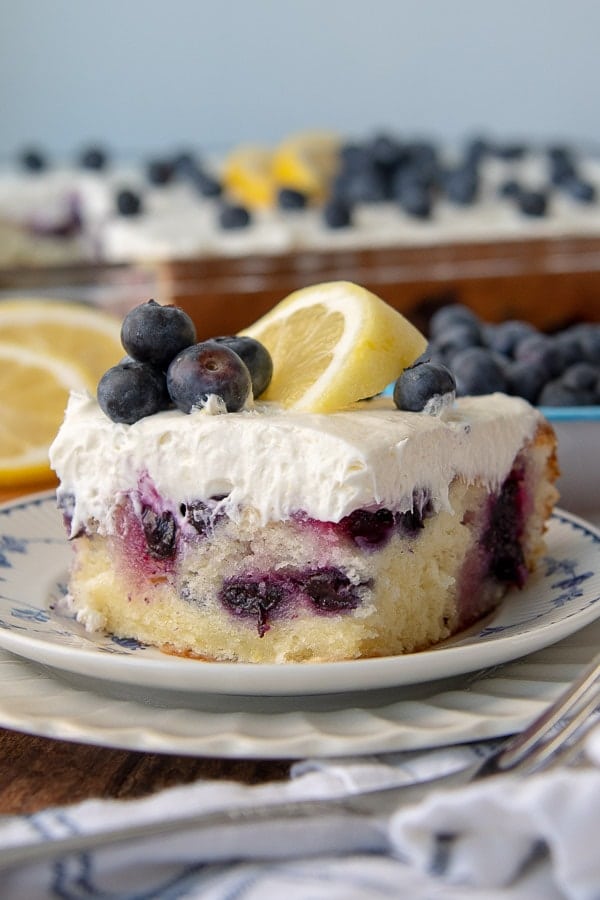 a close up of a cut piece of lemon blueberry cake on a stack of two plates