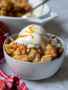 a bowl of apple crisp with ice cream and caramel on top