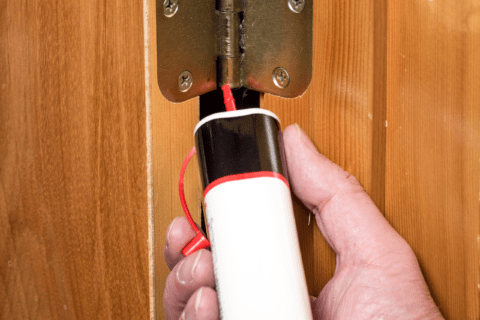 Applying oil to a door hinge.