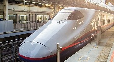 Treno shinkansen fermo in stazione, al tramonto.