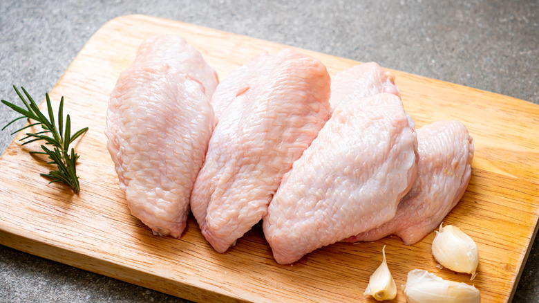 Raw chicken wings on a wooden board