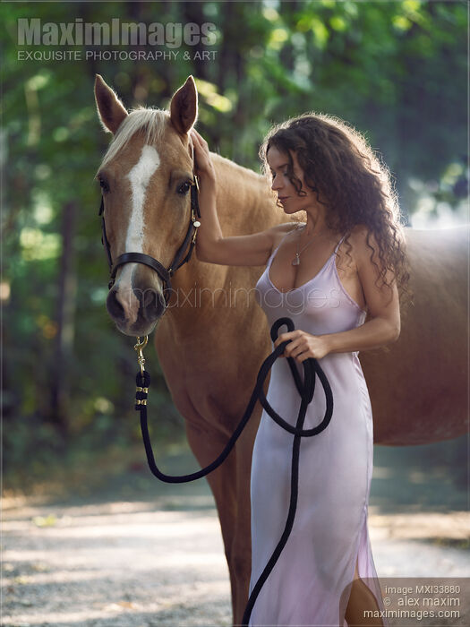 Beautiful sexy woman rider in elegant dress caressing a horse in nature with tranquil expression Stock Image MXI33880 © Alex Maxim / MaximImages