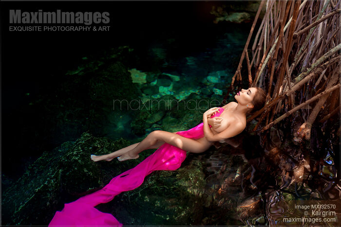 Sexy nude woman lying in clear water of a cenote covering her naked body with pink fabric Stock Image MXI32570 © Kai Grim / MaximImages