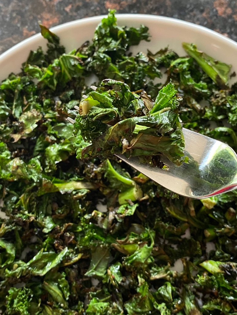 pan fried kale on a plate with fork picking some up