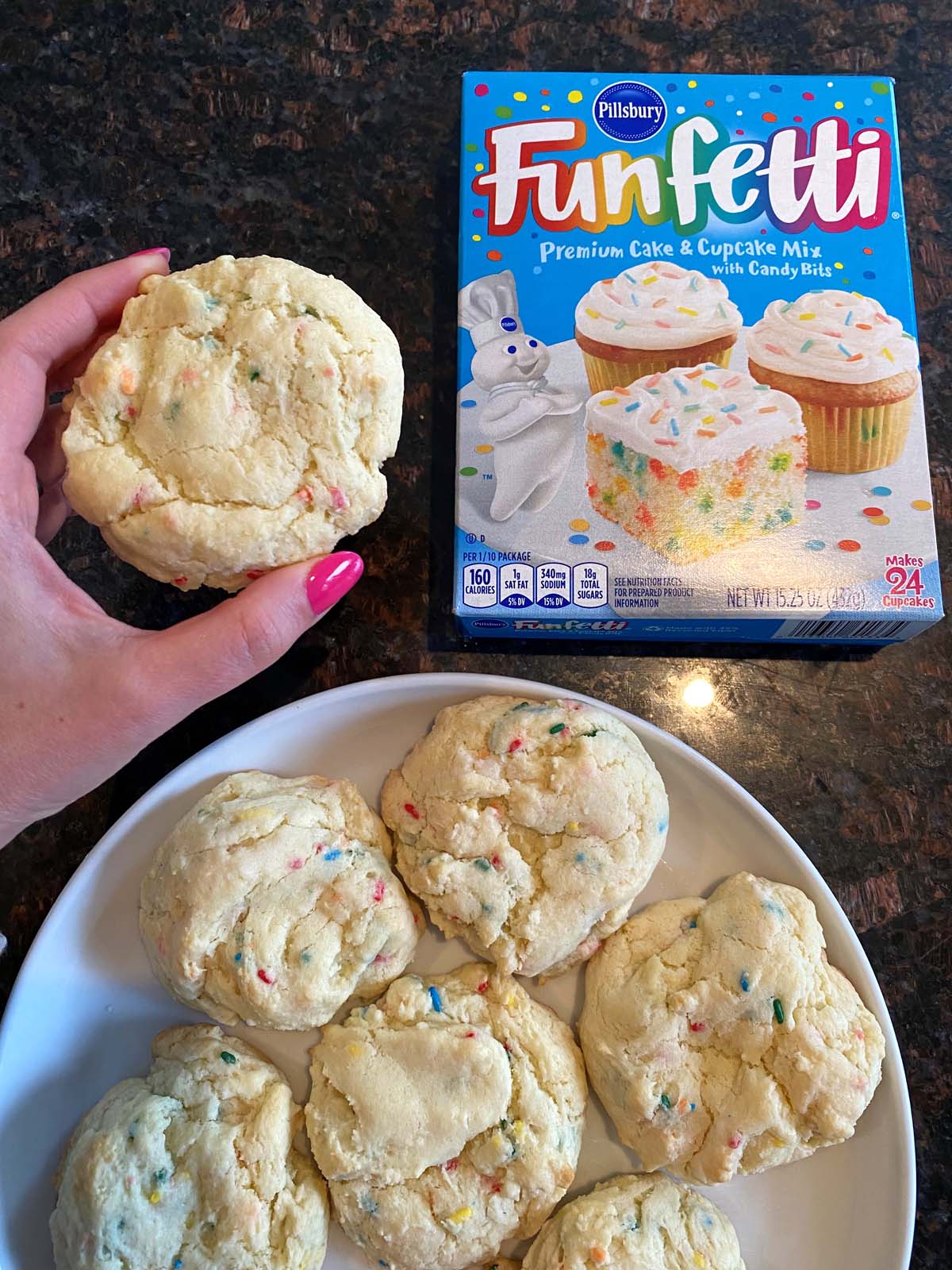 Funfetti cake mix cookies on a white plate and a box of funfetti cake mix.