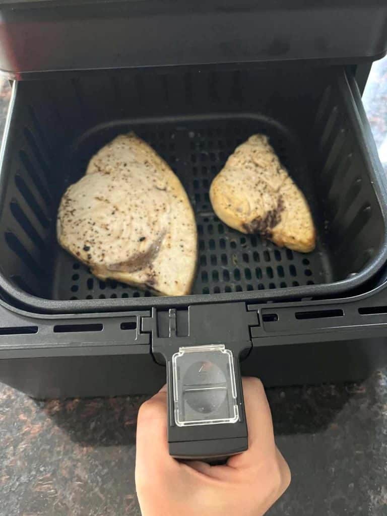 Two seasoned swordfish fillets cooking in an air fryer basket, demonstrating the simplicity of cooking frozen fish in an air fryer for a quick, healthy meal.