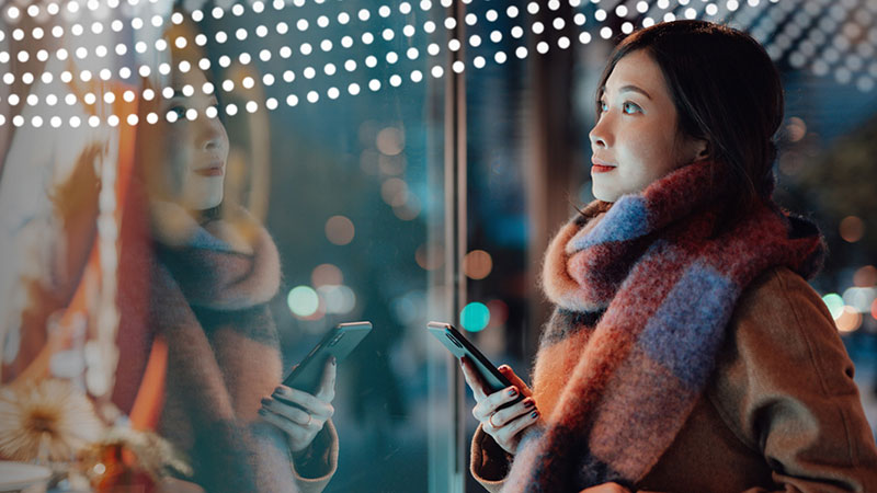 A woman in a colourful scarf looks at a shop window display