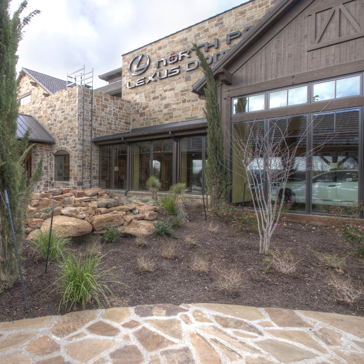 External view of dealership with plants and stone walkway.