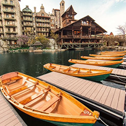 Several small boats separated by small docks on the lake in front of a large hotel in the background