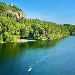 Image overlooking someone paddle boarding on a lake on a sunny day