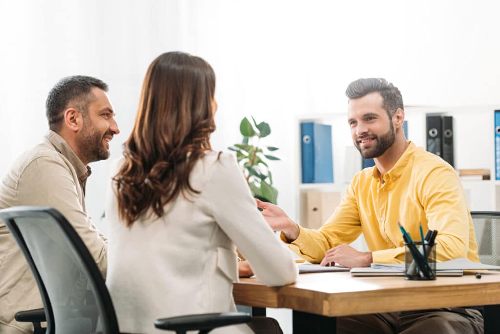 Credit counselor providing financial advice to a young couple in his office.