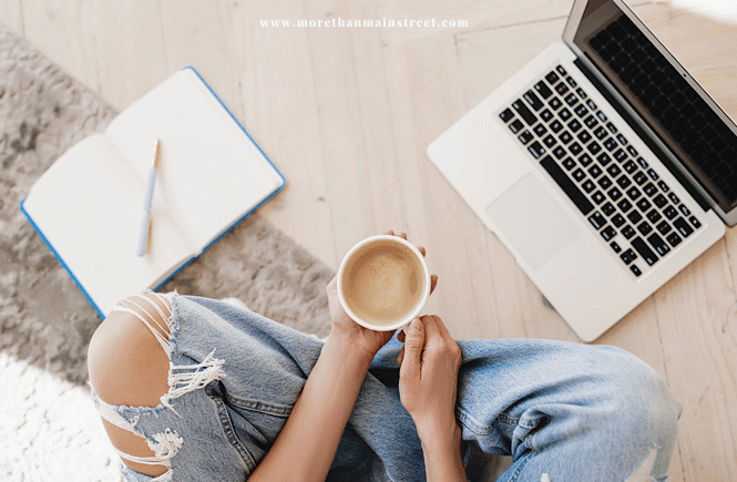 Person sitting cross legged with coffee, laptop, notepad and pen ready to work on self discovery questions.