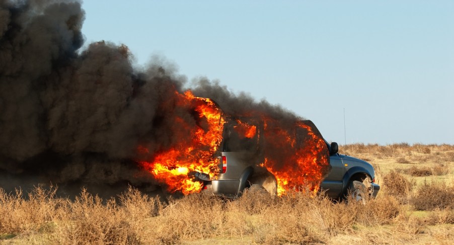 A truck that's on fire in a field