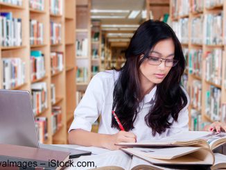 Young student writing a academic paper in the library