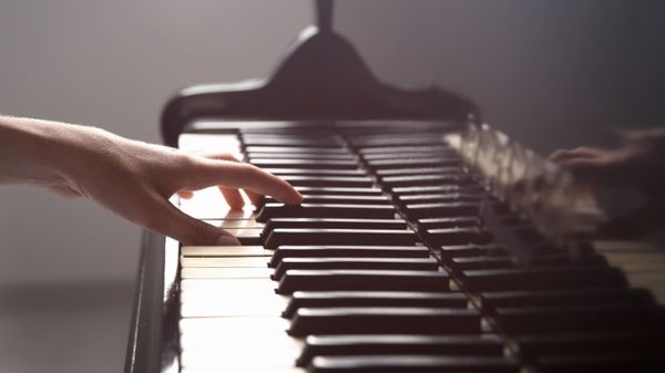 Image: one hand on the piano; article: 10 Engaging Piano Songs for the Neurodivergent Beginner